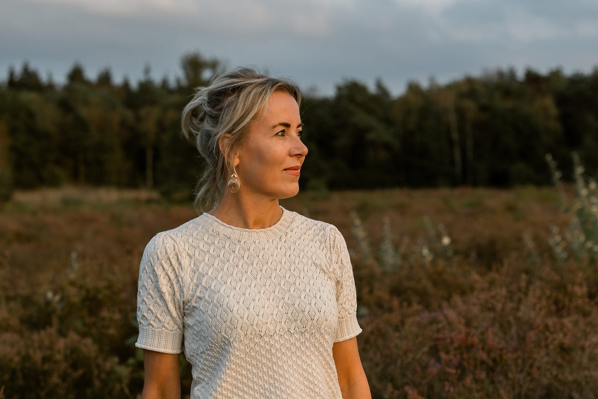 Mariëlle kijkt opzij, met de heide achter haar